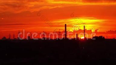 工业橙色日落。 太阳落在管道和电源塔后面。 4K实时长镜头
